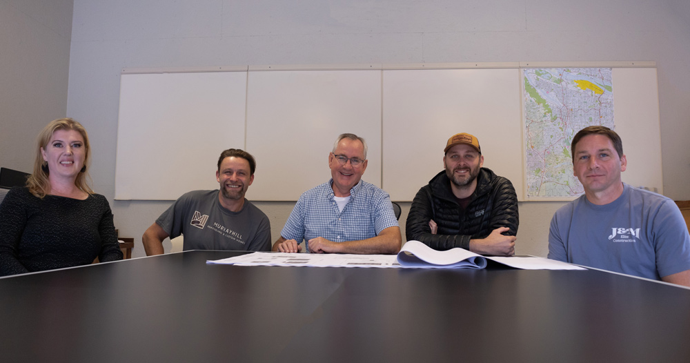 Murrayhill Remodeling core team gathered around a conference table reviewing project blueprints in their Beaverton, OR office